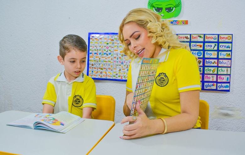 Profesora acompaña la lectura de un alumno en la mesa de trabajo