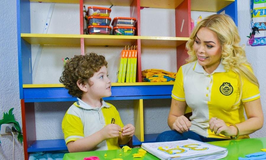 Alumno modela con plastilina junto a su profesora en el área de artes